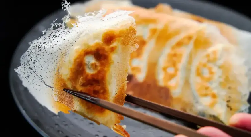 Chrupiące gyoza z delikatną, koronkową skórką, podniesione pałeczkami. Idealny przepis na gyoza!