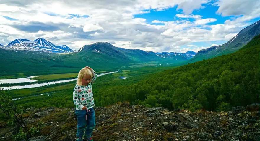 Ett barn funderar på den storslagna utsikten under en vandring med barn i fjällen.