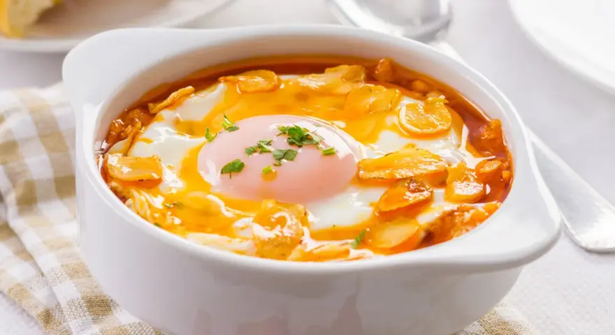 Sopa castellana en cuenco blanco con huevo escalfado y picatostes.