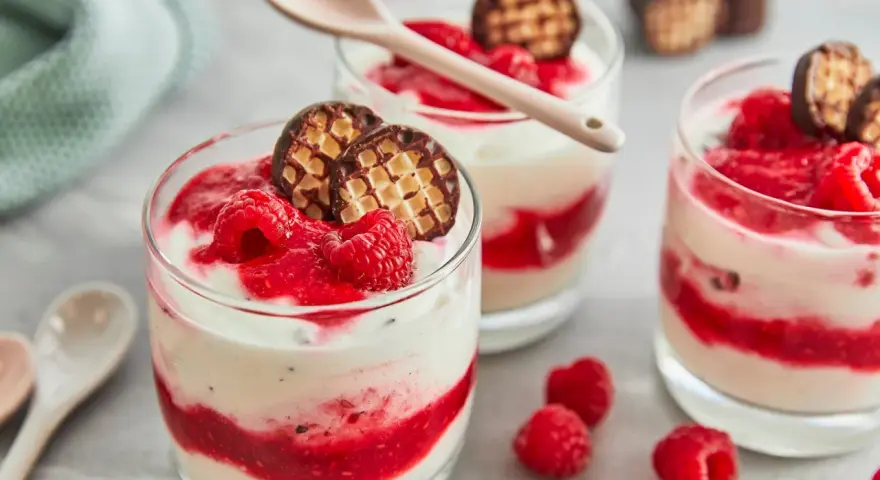 Schokokuss Dessert mit Mascarpone, Himbeeren und Schokowaffel-Keksen in Gläsern, garniert mit frischen Himbeeren.