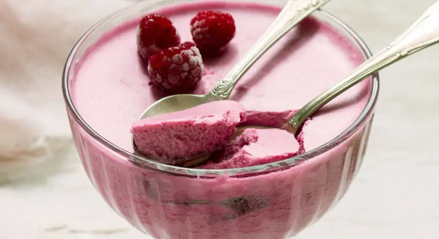 Himbeere-rotweincreme selbstgemacht in einer Glasschale, garniert mit frischen Himbeeren und zwei Löffeln.