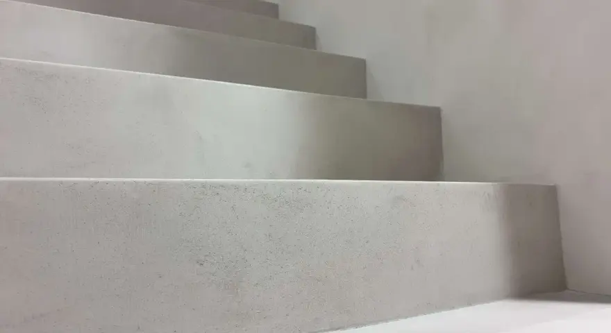 Nowoczesne schody z surowego betonu na klatce schodowej. Minimalistyczny design, jasnoszare stopnie.