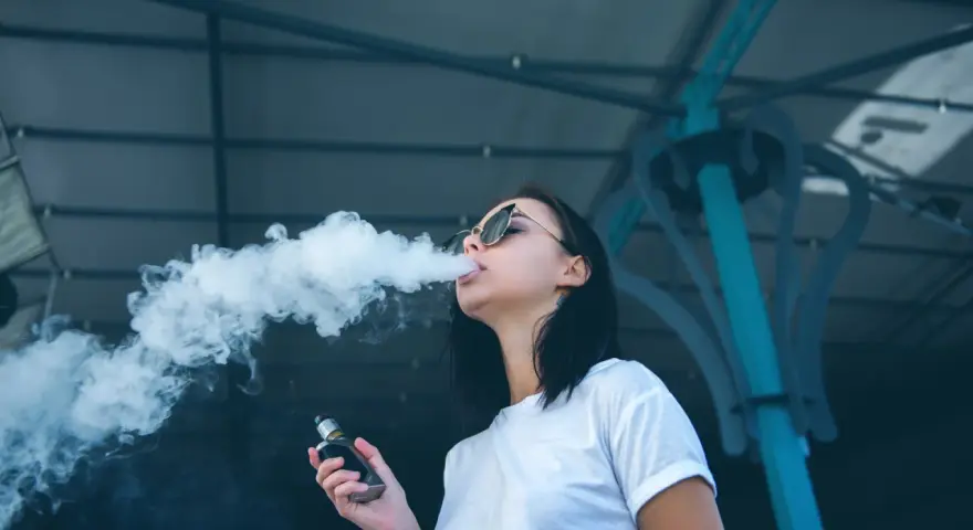 Joven exhala humo de un vaper, una práctica que demuestra que el vaper es malo para la salud.