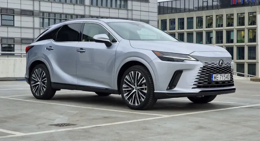 Srebrny Lexus RX 350h zaparkowany przed nowoczesnym budynkiem.