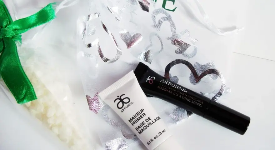 Arbonne opinie: zestaw kosmetyków z primerem i tuszem, w ozdobnym woreczku.