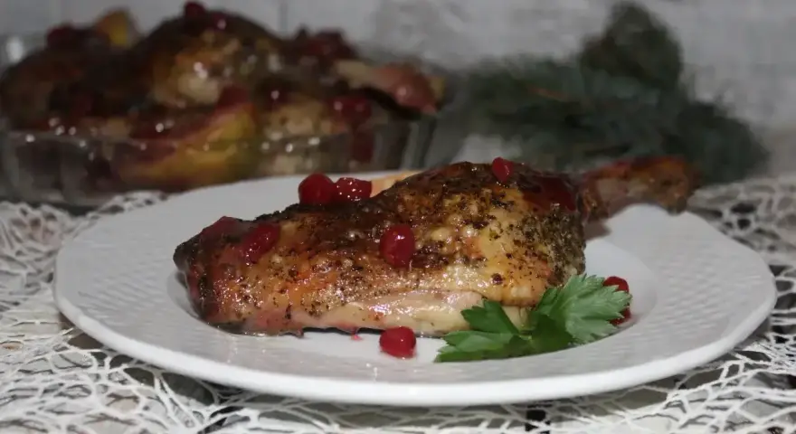 Pyszne, pieczone udka z kaczki z żurawiną i ziołami, podane na białym talerzu.