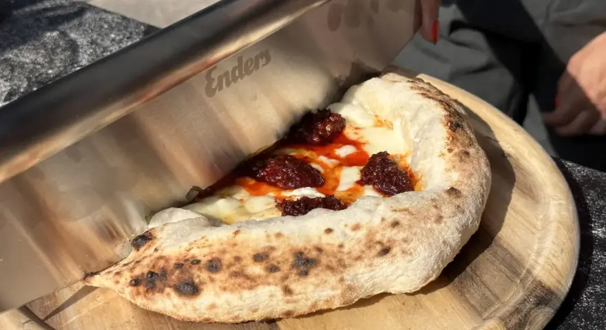 Ein Messer schneidet ein Stück Pizza mit geschmolzenem Käse und würziger Tomatensauce. Der luftige pizzateig napoli ist perfekt gebacken.