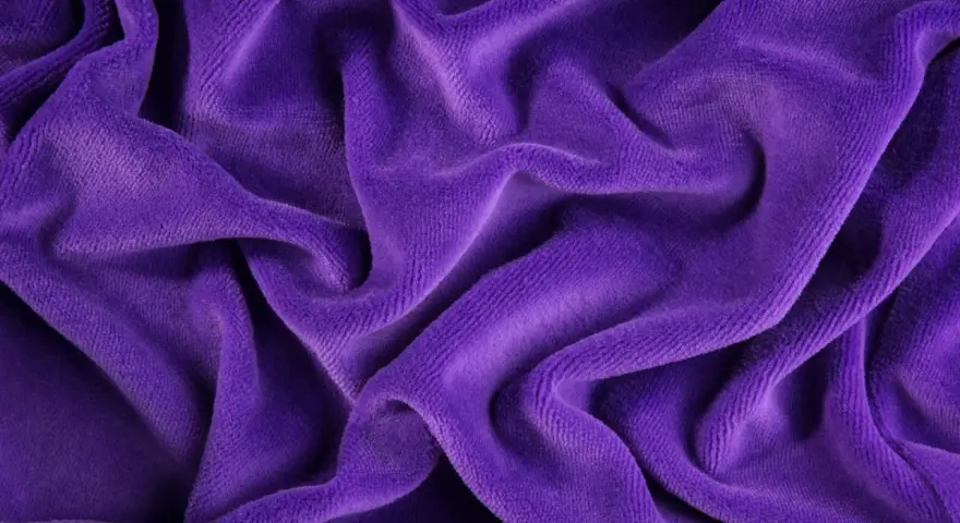 Ondeggiante velour tessuto viola, morbido e invitante, con pieghe profonde che creano un gioco di luci e ombre.
