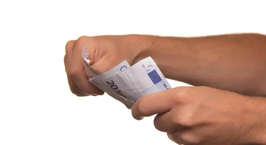 Dłonie trzymają banknoty euro. To może być symboliczne zawiadomienie o uchyleniu zajęcia, gdy pieniądze wracają do właściciela.