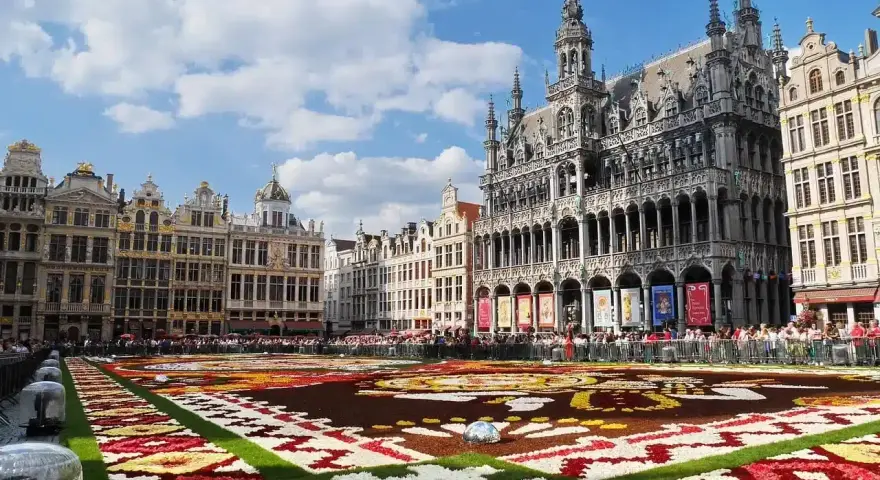Grand Place, Brussels, with a vibrant flower carpet and ornate buildings under a blue sky.