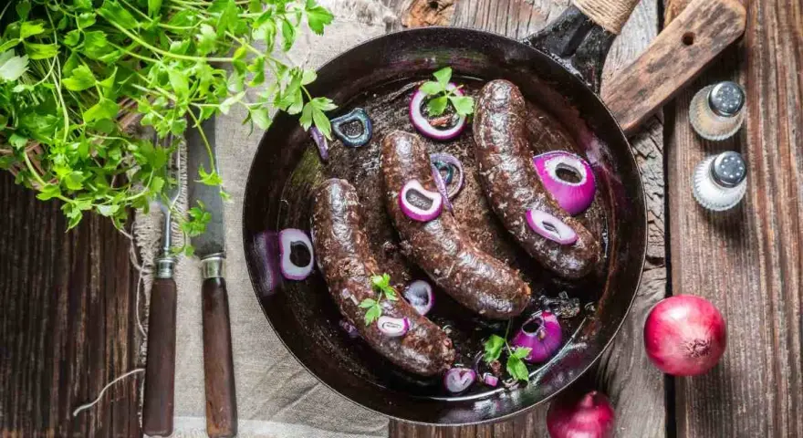 Smażona kaszanka z cebulą na patelni, idealna na keto. Świeża natka pietruszki dodaje aromatu.