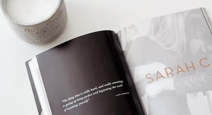 Otwarta książka z cytatem o tym, jak znaleźć swój styl, obok świecy. Na stronie widnieje napis "SARAH C".