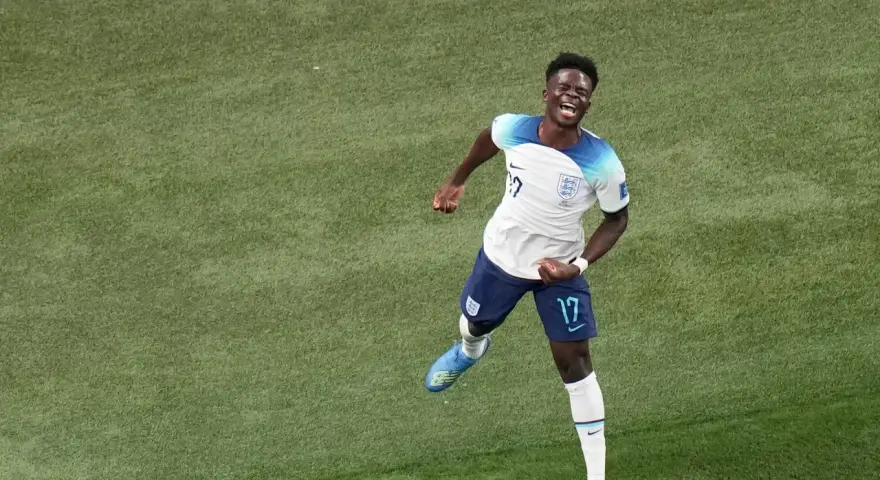 Bukayo Saka celebra un gol con euforia en el campo de fútbol.