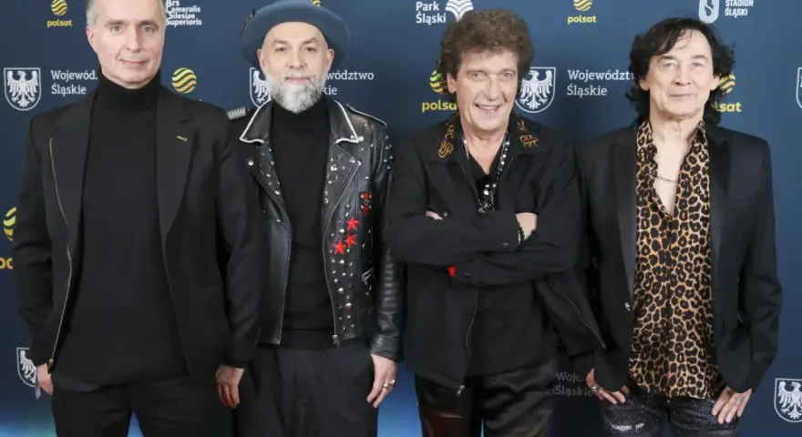 Czterech mężczyzn, w tym legendy polskie zespoły muzyczne lat 70-80, pozuje na ściance.
