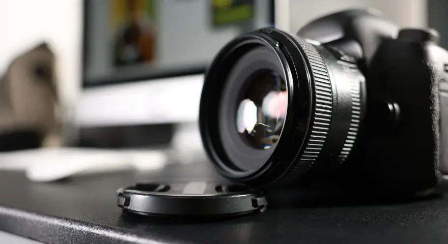 Czarne body lustrzanki cyfrowej z obiektywem i dekielkiem na czarnym blacie. Zastanawiasz się dslr co to? To właśnie to!
