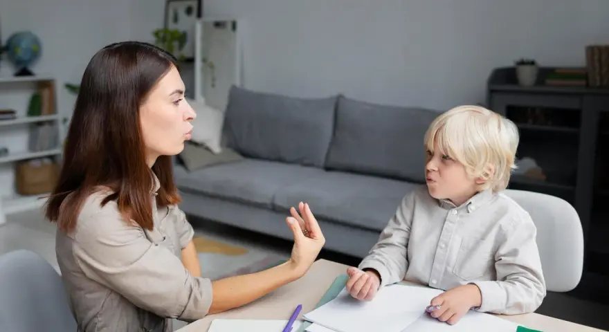 Terapeuta pracuje z dzieckiem, które ma orzeczenie o specjalnych potrzebach edukacyjnych, ćwicząc wymowę.