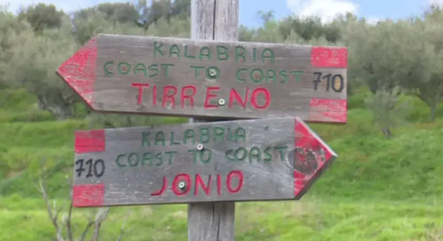 Cartelli in legno indicano il percorso "Kalabria Coast to Coast": uno punta a Tirreno, l'altro a Jonio.