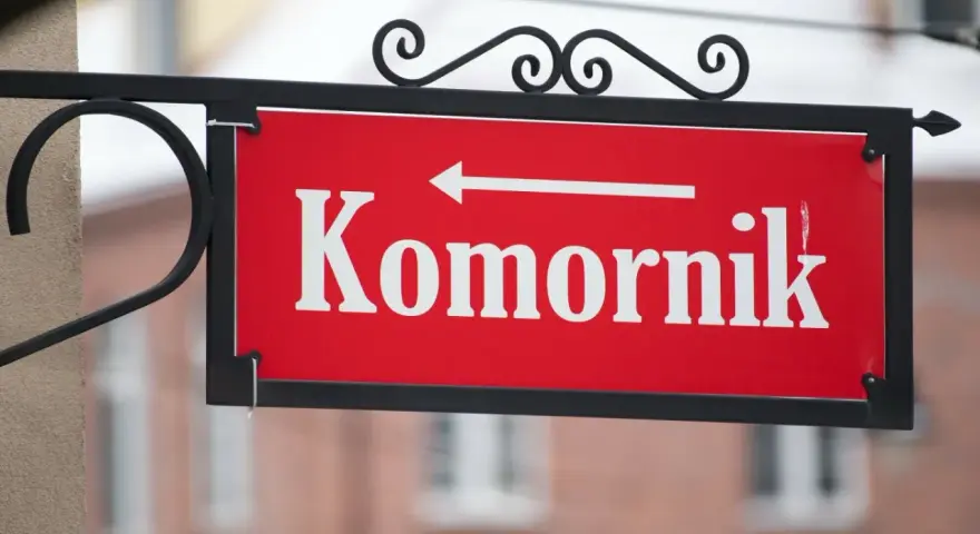 Czerwona tabliczka z napisem "Komornik" i strzałką w lewo. Pamiętaj, czego nie może zabrać komornik z mieszkania!