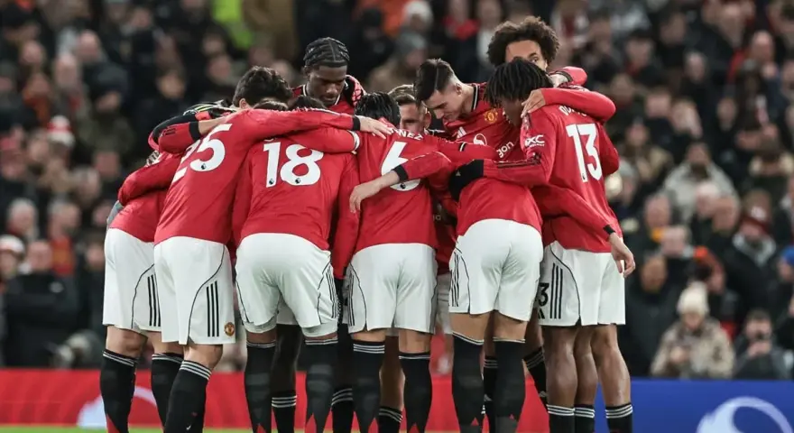 Piłkarze Manchesteru United w czerwonych strojach tworzą zwarty krąg, jednocząc się przed meczem. Ich wspólne united transfery budują ducha drużyny.