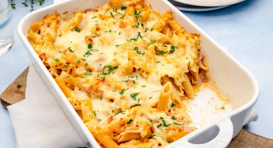 Herzhaftes Nudel Schinken Gratin mit geschmolzenem Käse und Petersilie, bereit zum Servieren.