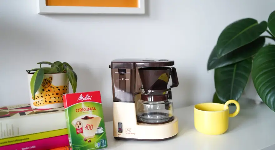 Kawiarka przelewowa Melitta Aromaboy gotowa do zaparzenia porannej kawy. Obok filtry i żółta filiżanka.