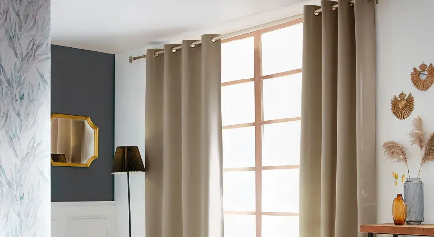 Eine schicke Gardinenstange anbringen, um die beige Vorhänge über dem Fenster zu befestigen. Dekorative Elemente wie Spiegel und Pflanzen ergänzen den Raum.