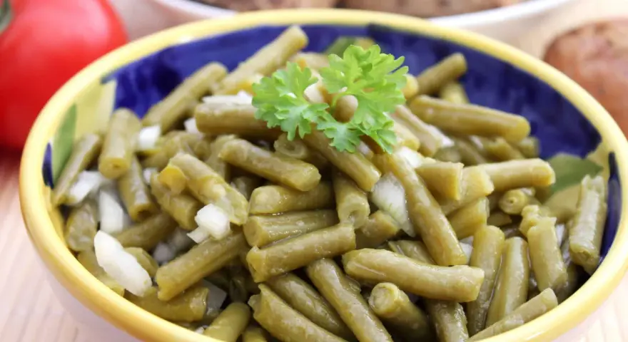 Bohnensalat rezept: Ein bunter Napf mit grünen Bohnen, Zwiebeln und Petersilie, bereit zum Servieren.