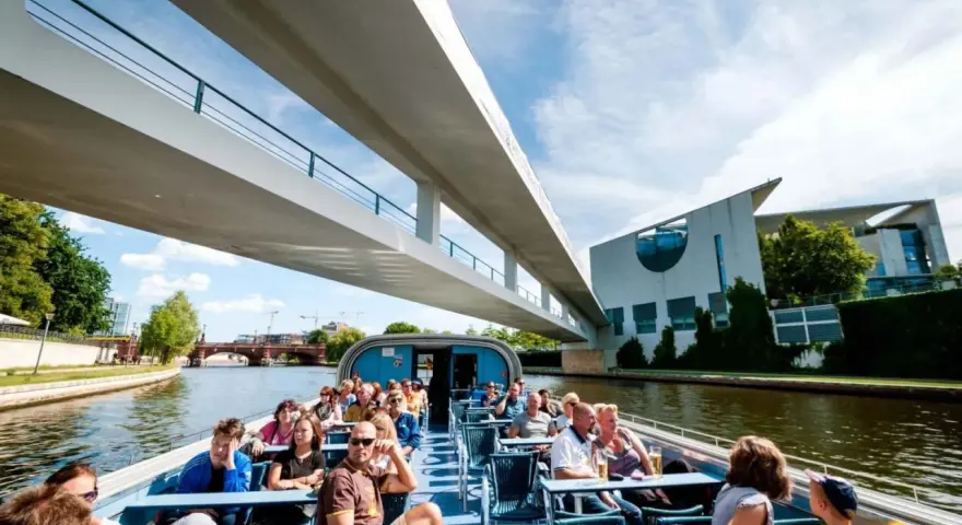 Bootsfahrt auf der Spree in Berlin unter einer modernen Brücke mit Blick auf das Regierungsviertel.