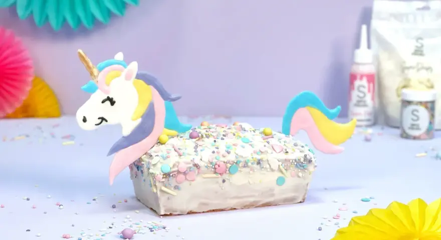 Ein magischer einhorn kuchen, verziert mit bunten Streuseln und einem süßen Einhorn-Topper, bereit für eine märchenhafte Feier.