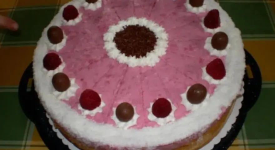 Eine köstliche Kokos Himbeer Torte, verziert mit Schokolade und frischen Himbeeren, bereit zum Genießen.