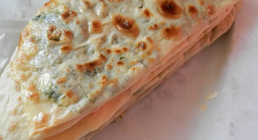 Gozleme épinard, une crêpe turque dorée et pliée, garnie d'épinards frais et savoureux.