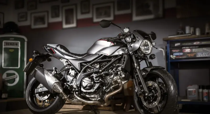 Srebrny motocykl Suzuki SV650X z czarną ramą i detalami, stojący w garażu.