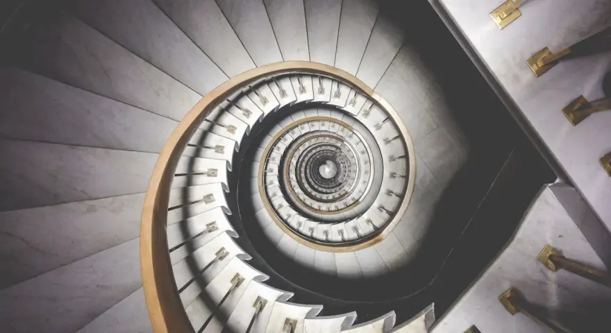 Kręcone schody z marmuru i drewna, tworzące spiralę przypominającą ciąg Fibonacciego w architekturze.