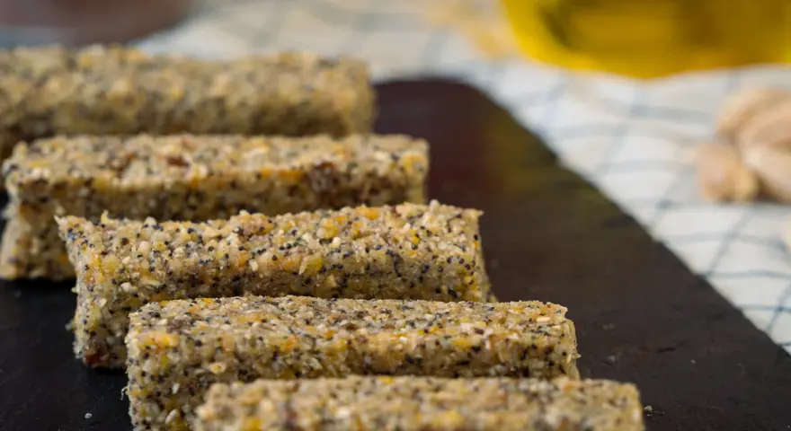 Barritas energéticas caseras de cereales y semillas en una tabla de pizarra.