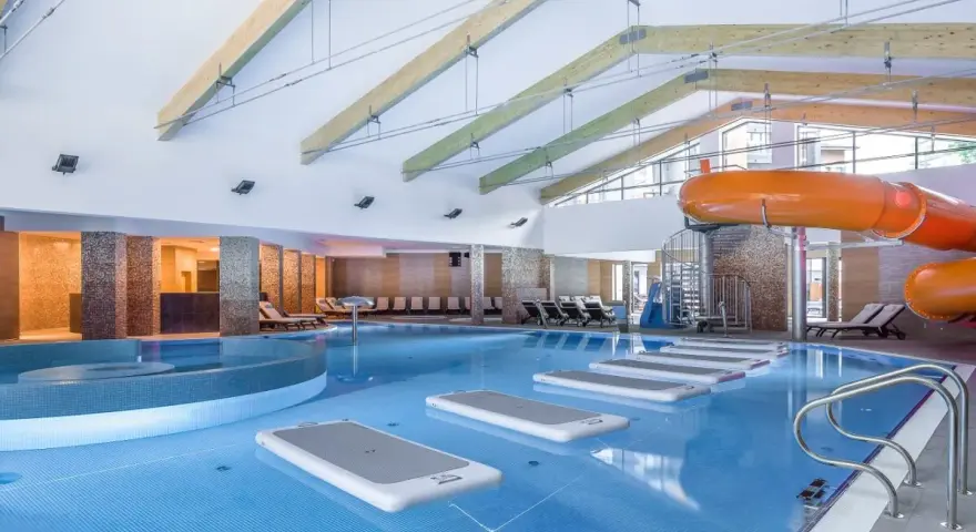 Wodne szaleństwo w hotelu z basenami w górach: zjeżdżalnia, jacuzzi i dmuchane wyspy na wodzie.