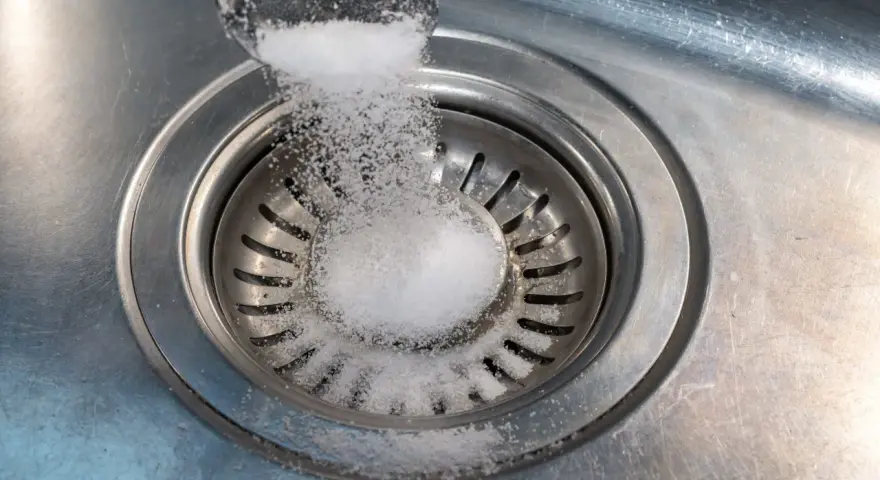 Salt hälls ner i diskhoavloppet. En skopa med salt sprids över silen.