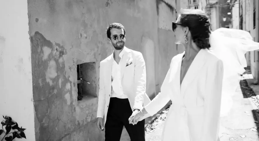 Un couple marié, main dans la main, traverse une ruelle. Ils pensent déjà aux démarches administratives après mariage au service public.