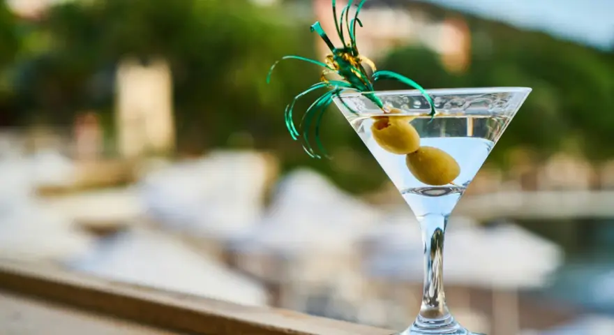 Idealny drink na wakacje: schłodzone martini z dwiema oliwkami, ozdobione zieloną wstążką. Idealne co do martini.