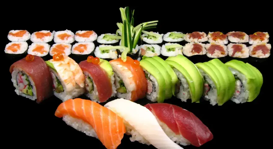 Różnorodne sushi: nigiri z łososiem, tuńczykiem i białą rybą, rolki z awokado, krewetką, tuńczykiem i ogórkiem. Idealne na początek nauki, jak jeść sushi.