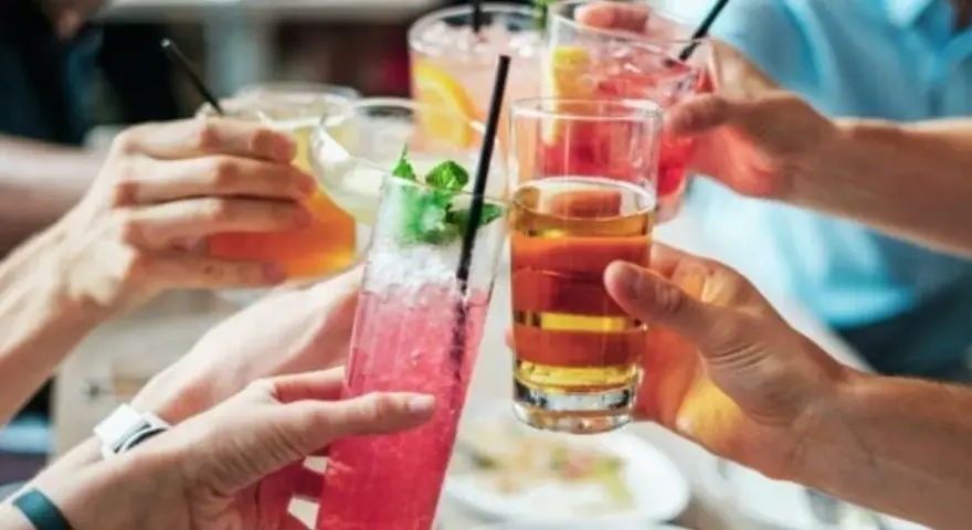 Ludzie wznoszą toasty kolorowymi drinkami. Zastanawiasz się, ile alkoholu można wziąć do Norwegii?