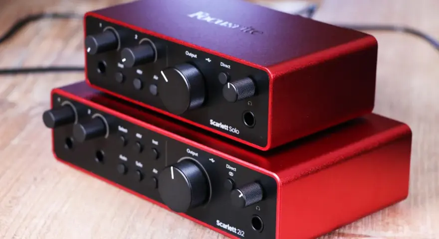 Dwa czerwone interfejsy audio Focusrite Scarlett Solo 3gen i Scarlett 2i2 ułożone jeden na drugim.