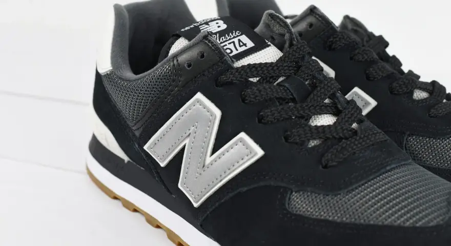 Czarne buty New Balance 574 z szarym logo "N" i gumową podeszwą. Czy Sizeer ma oryginalne buty? Tak, te wyglądają na autentyczne.