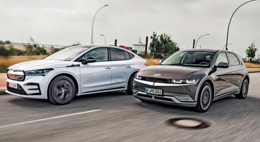 Dwa elektryczne samochody jadące obok siebie. Po prawej stronie ciemnoszary Hyundai Ioniq 5, po lewej biała Skoda. Zastanawiasz się nad ich zasięg?