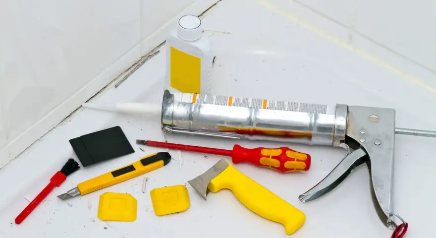 Attrezzi per la rimozione olio di silicone e sigillatura: pistola per silicone, taglierino, spatole, pennello e solvente.