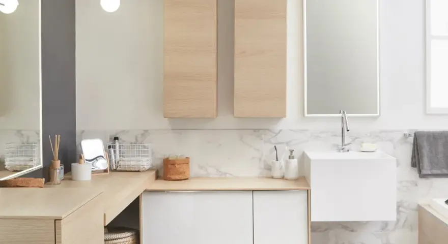 Salle de bain moderne avec un lavabo évier suspendu, des meubles en bois clair et un grand miroir éclairé.