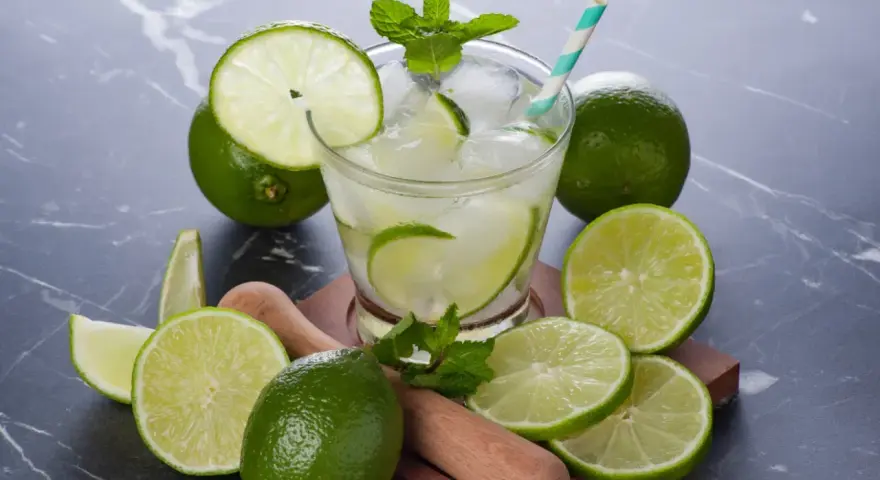 Orzeźwiająca Caipirinha przepis: świeże limonki, lód, mięta i drewniany muddler. Idealny drink na lato.