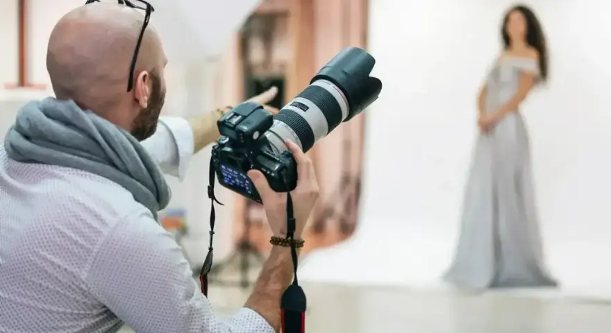 Fotograf z aparatem przygotowuje sesję. Zastanawiasz się, ile kosztuje fotograf na 18. urodziny?