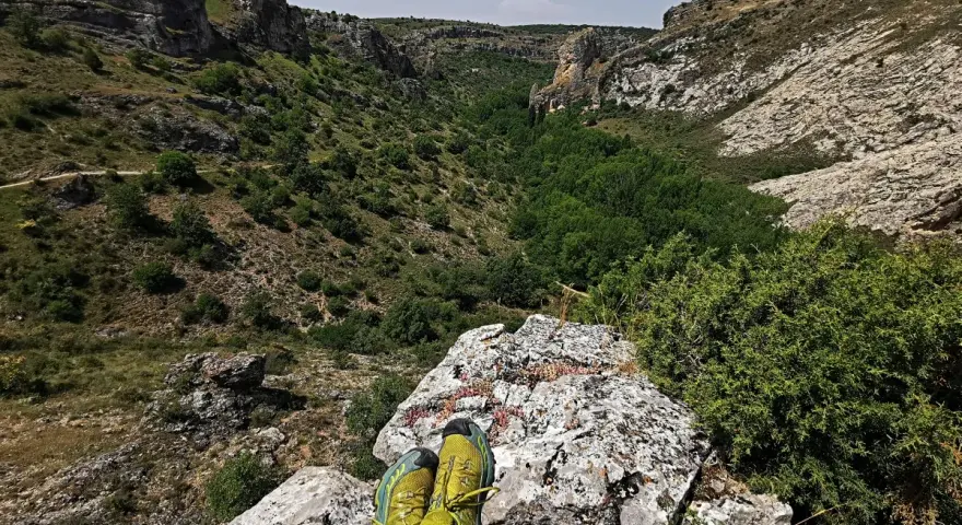 Botas de trail running sobre roca, contemplando el cañón del río Dulce en Guadalajara.