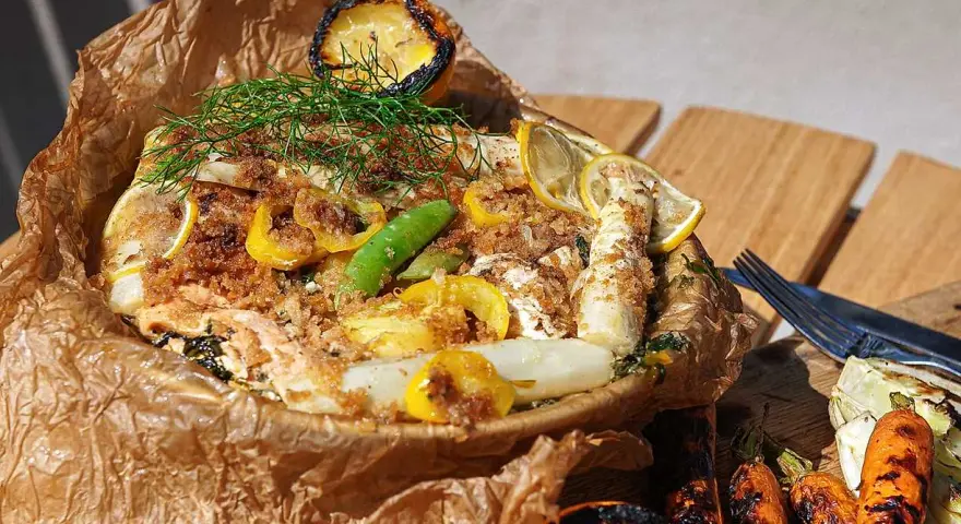 En saftig fiskpaket på grillen med citron, sparris och dill. Serveras med grillade grönsaker.
