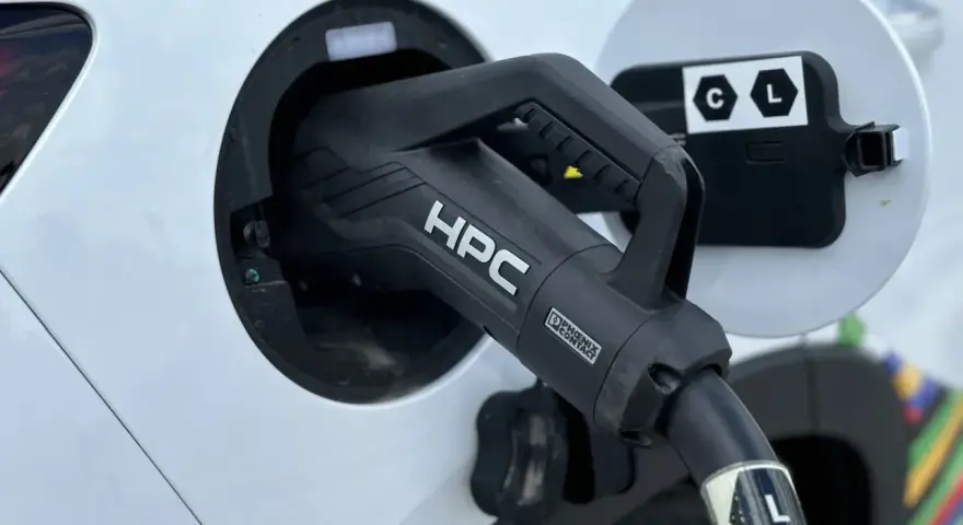 Ładowanie samochodu elektrycznego. Wtyczka HPC podłączona do portu ładowania, zapewniająca przepływ napięcia.
